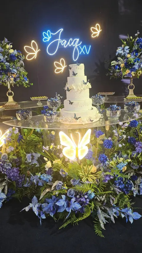 Mesa de festa de 15 anos com borboleta em neon LED e flores azuis